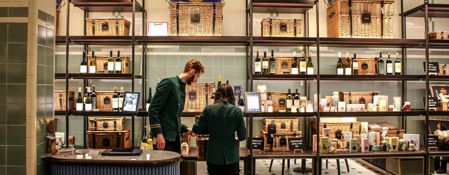 two shop attendants in harrods in front of a luxurious food display london
